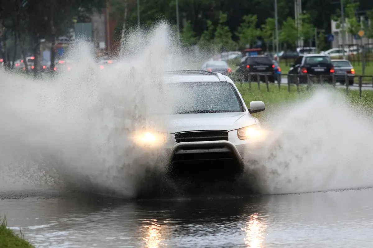 Sell a flood-damaged car in Houston: suv driving through deep water on a flooded road SUV driving through deep water on a flooded road, how drivers end up needing to sell a flood-damaged car in Houston