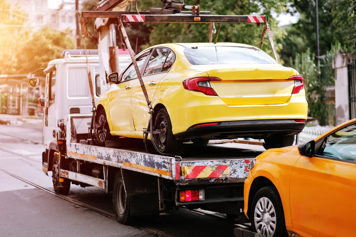 Texas impound fees: tow truck hauling a car to a storage lot Tow truck hauling a car to a storage lot, where Texas impound fees start adding up