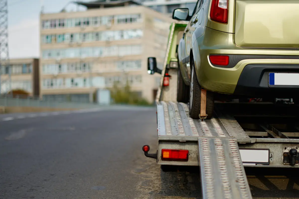 Broken car on a flatbed tow truck, the moment a no-title junk car price often drops