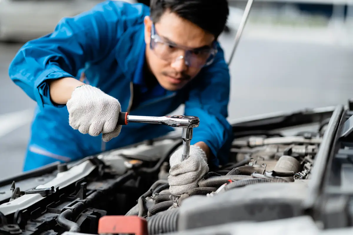 Junk car offer drop at pickup: mechanic checking an engine Mechanic checking an engine, the curbside inspection behind a junk car offer drop at pickup