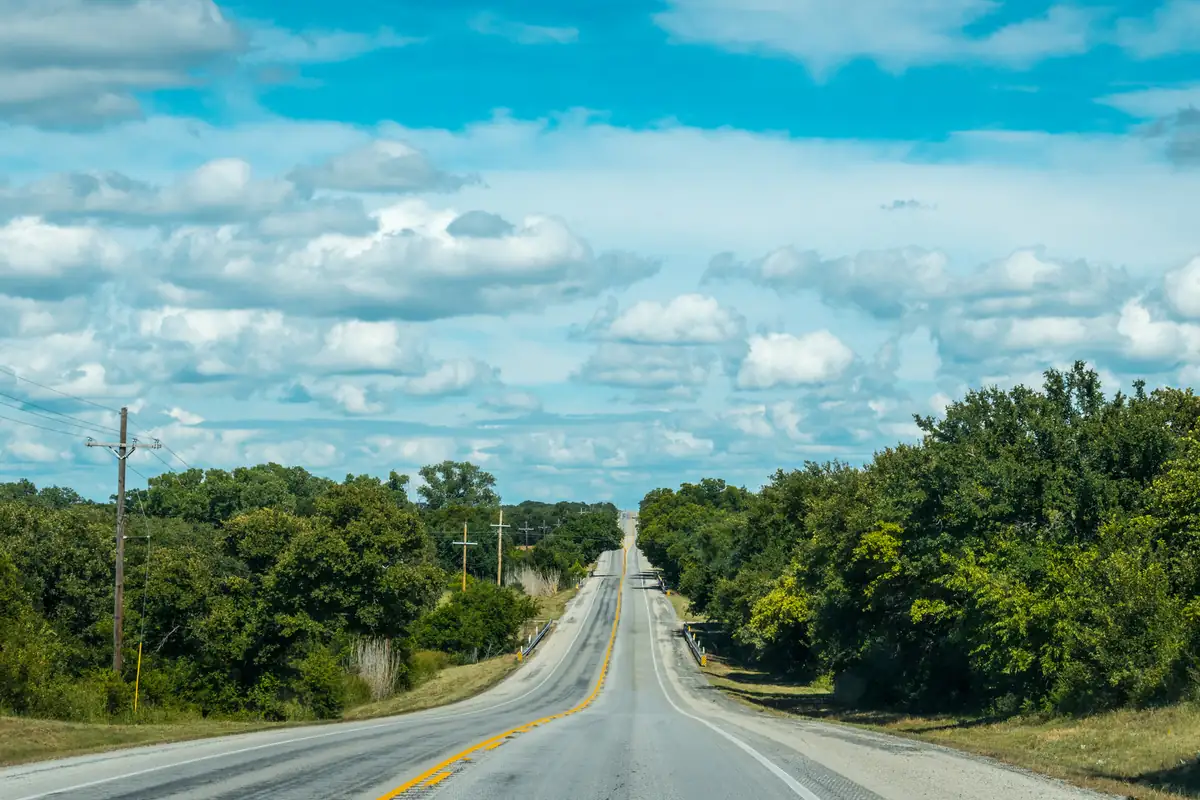 Long two-lane road through the Texas countryside, the distance problem when you sell a junk car in rural Texas