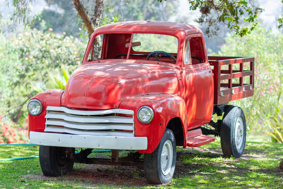 Old red farm truck parked on a ranch, a typical vehicle people sell as a junk car in rural Texas