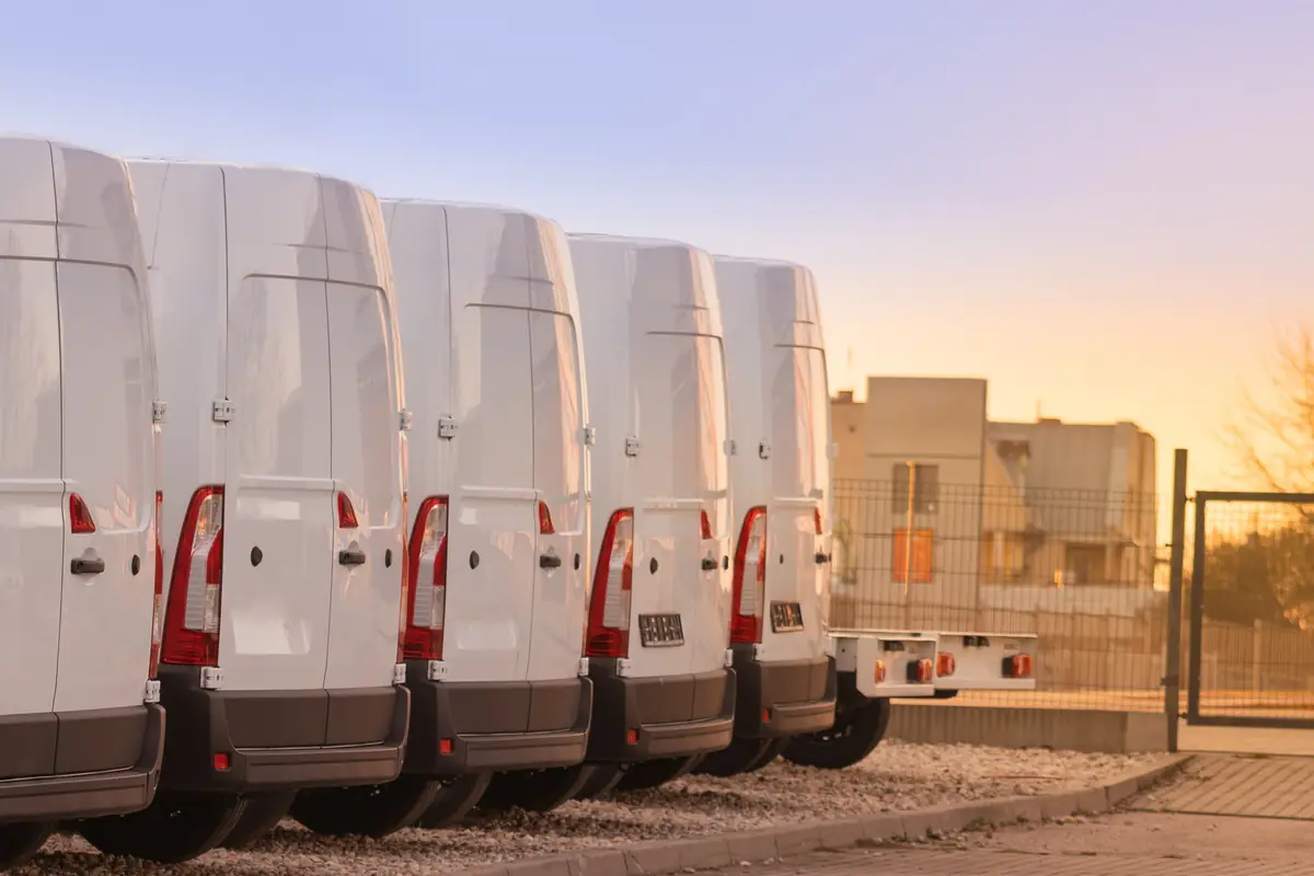 Sell a fleet vehicle in Texas: row of white commercial vans parked at a depot Row of white commercial vans parked at a depot, ready to sell a fleet vehicle in Texas