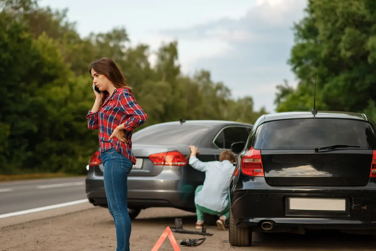 Young driver on the phone beside a crashed car, the scene after a teen totaled their first car in Texas