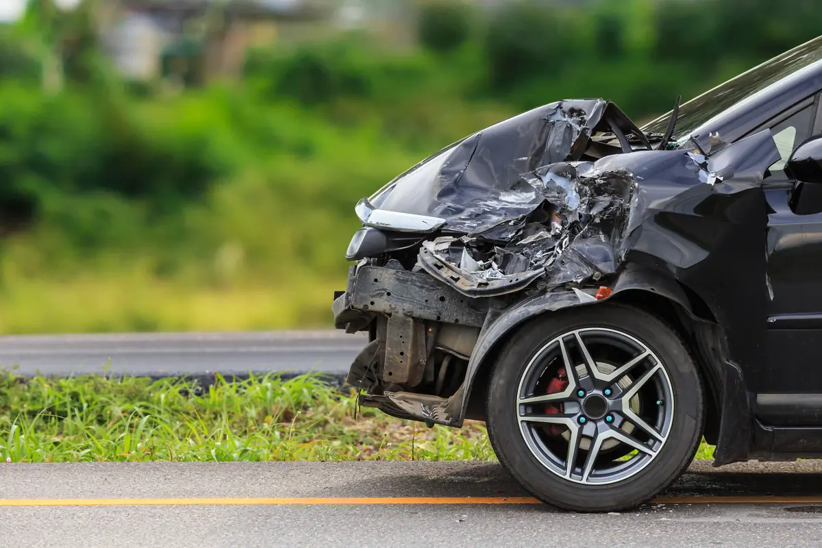 Black car with a wrecked front end on a roadside, a typical total loss offer in Texas case