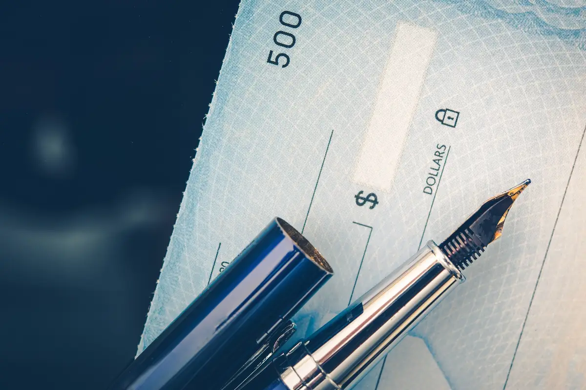 Pen writing a settlement check, the payout in a total loss offer in Texas