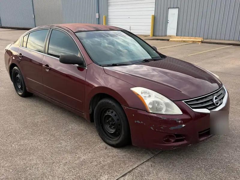 Maroon 2010 Nissan Altima 2.5 S junk car bought for $1,300 in Humble, TX. Peeling front bumper paint.