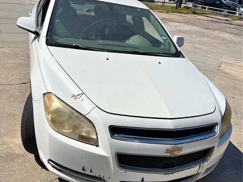 White 2011 Chevrolet Malibu 2LT junk car bought for $300 in Spring, TX. Faded headlights, chipped bumper.